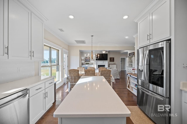 kitchen with dark wood-type flooring, white cabinetry, stainless steel appliances, and a kitchen island