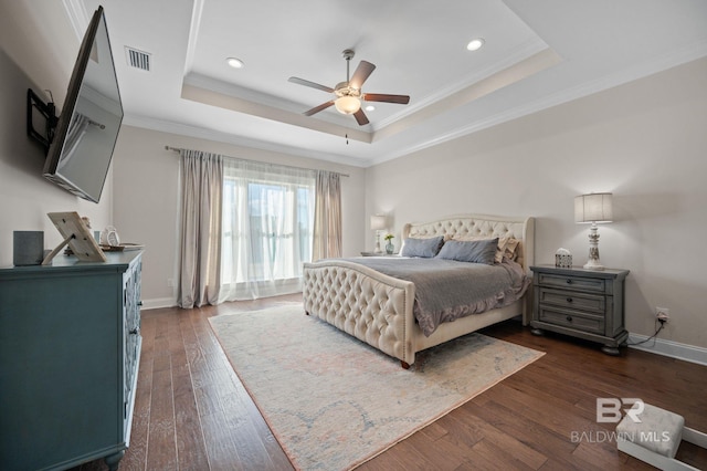 bedroom with ceiling fan, dark wood-type flooring, a tray ceiling, and crown molding