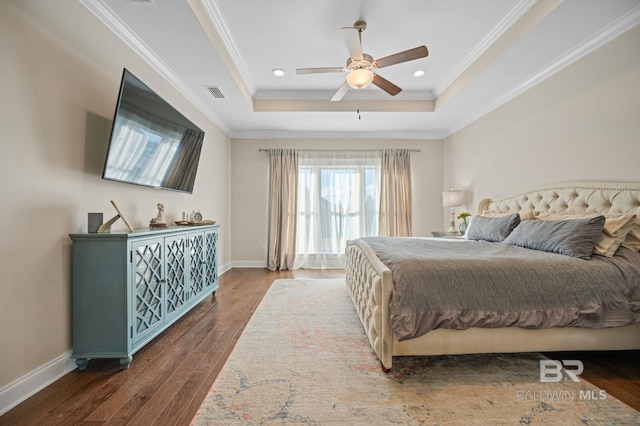 bedroom with ceiling fan, a tray ceiling, dark hardwood / wood-style floors, and crown molding