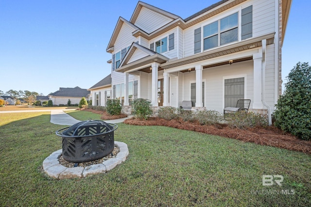 craftsman-style home with covered porch, a front yard, and a fire pit