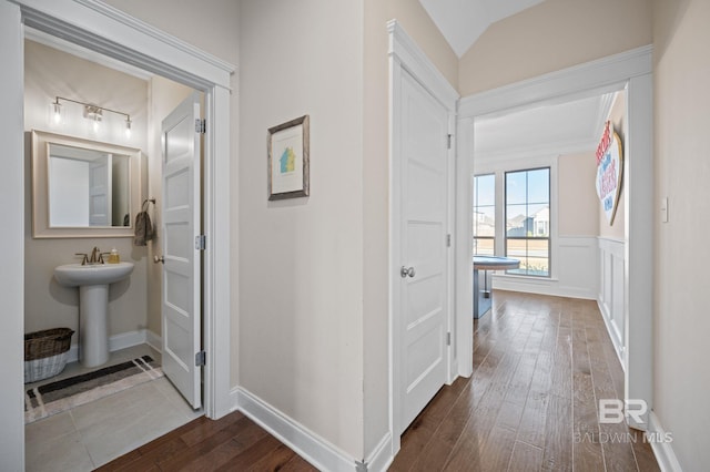 corridor with lofted ceiling, hardwood / wood-style flooring, and sink