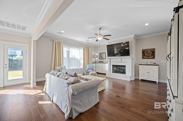 living room featuring a brick fireplace, plenty of natural light, and ornamental molding