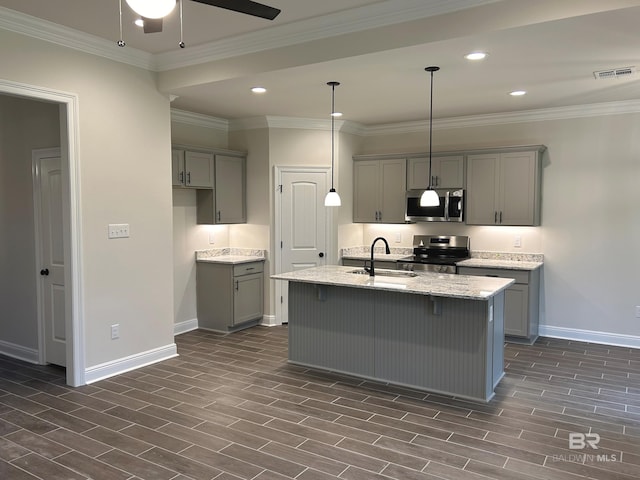 kitchen with sink, gray cabinetry, stainless steel appliances, light stone counters, and an island with sink