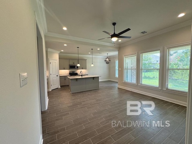 kitchen with stainless steel appliances, ornamental molding, pendant lighting, and a center island with sink