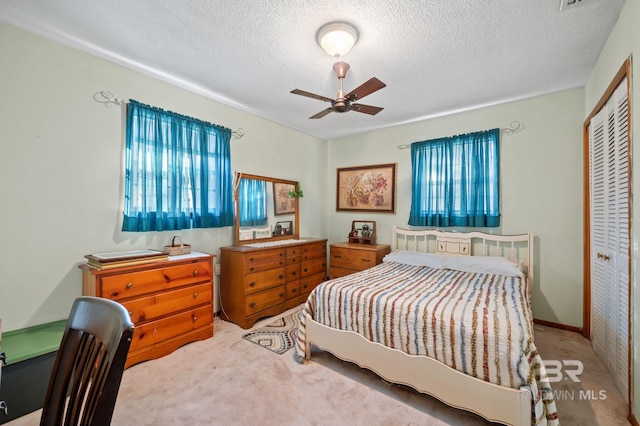 bedroom with light carpet, a textured ceiling, a closet, and ceiling fan