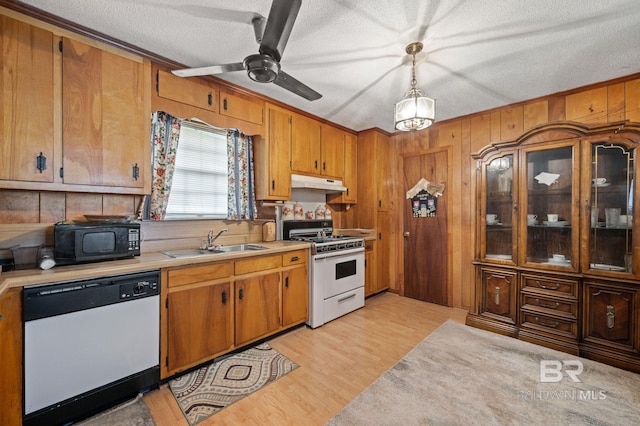 kitchen featuring sink, a textured ceiling, pendant lighting, white appliances, and light hardwood / wood-style floors