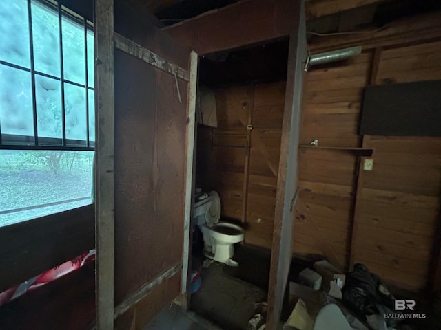 interior space featuring wood walls and toilet