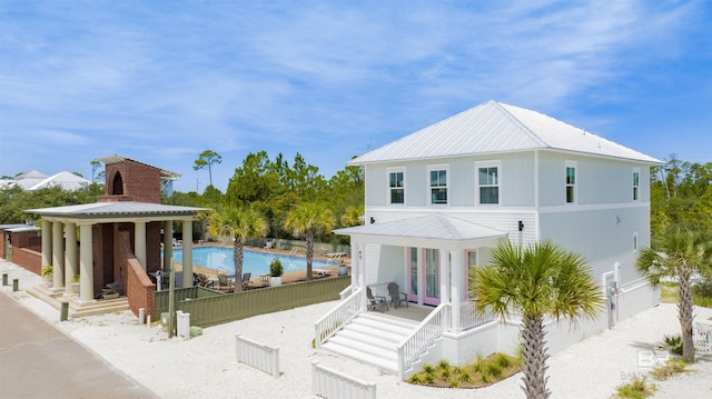 exterior space with metal roof, a fenced in pool, and french doors