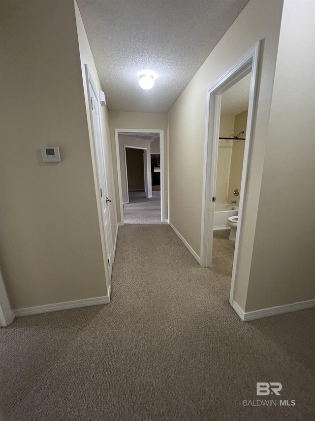 hall featuring a textured ceiling and carpet flooring