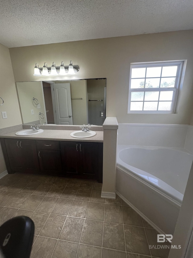 bathroom featuring tile patterned floors, vanity, a textured ceiling, and a tub