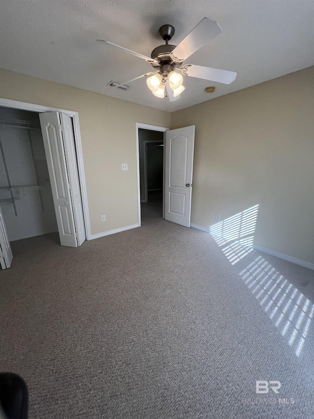 unfurnished bedroom with a textured ceiling, carpet floors, a closet, and ceiling fan