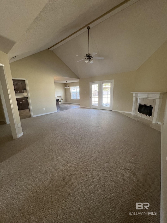 unfurnished living room featuring lofted ceiling, a textured ceiling, ceiling fan, a tiled fireplace, and carpet