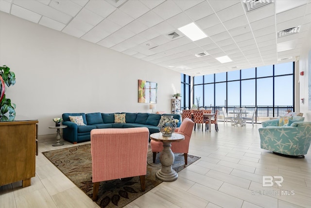 living room featuring visible vents, a paneled ceiling, and floor to ceiling windows