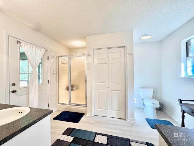 bathroom with vanity, a shower with shower door, and a textured ceiling