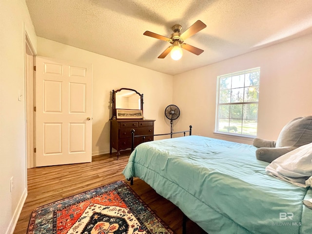 bedroom featuring hardwood / wood-style floors, ceiling fan, and a textured ceiling