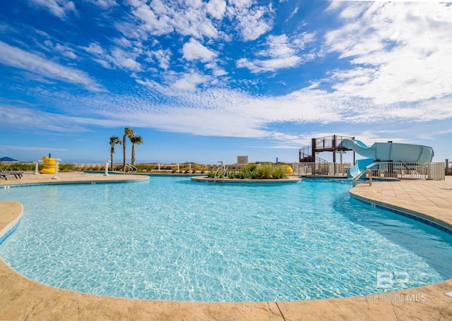 community pool with a patio area and a water slide