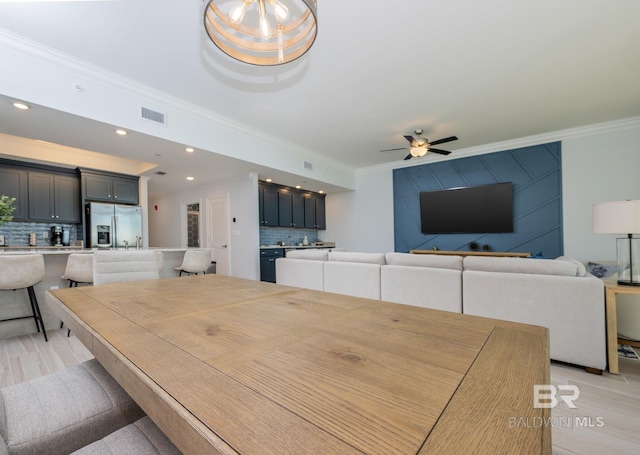 dining area featuring ornamental molding, a ceiling fan, wet bar, and visible vents