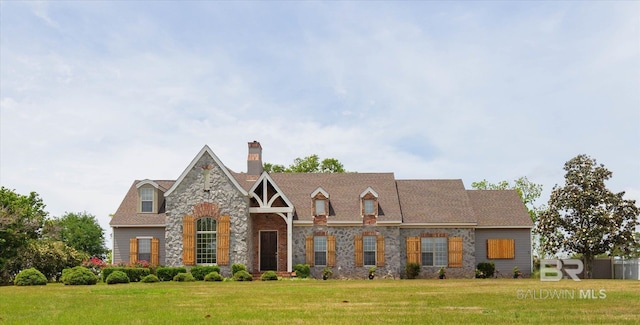 view of front facade with a chimney, a front yard, and stone siding