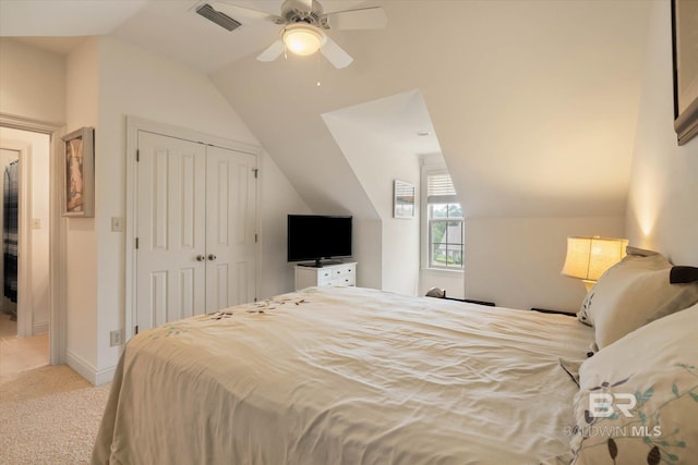 bedroom featuring visible vents, ceiling fan, a closet, vaulted ceiling, and light carpet