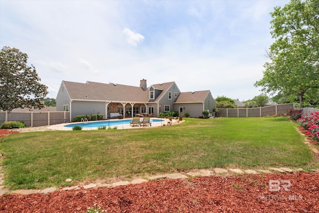 rear view of house featuring a chimney, a fenced backyard, a yard, and a fenced in pool
