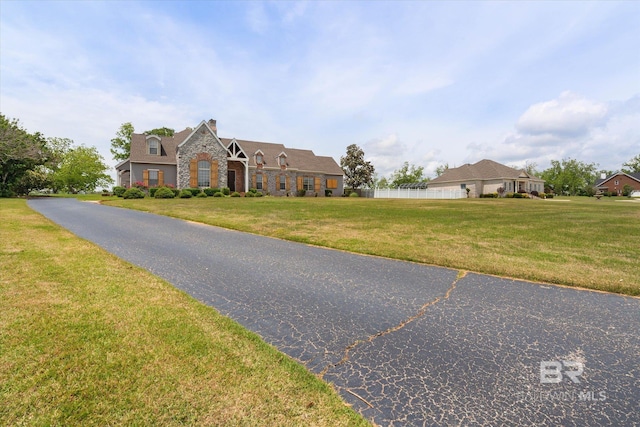 view of front of property with a front yard, fence, stone siding, and a chimney
