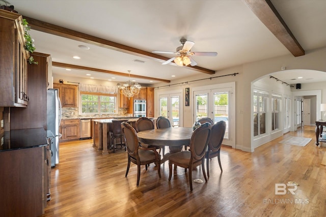 dining room featuring light wood-type flooring, ceiling fan with notable chandelier, beamed ceiling, and arched walkways