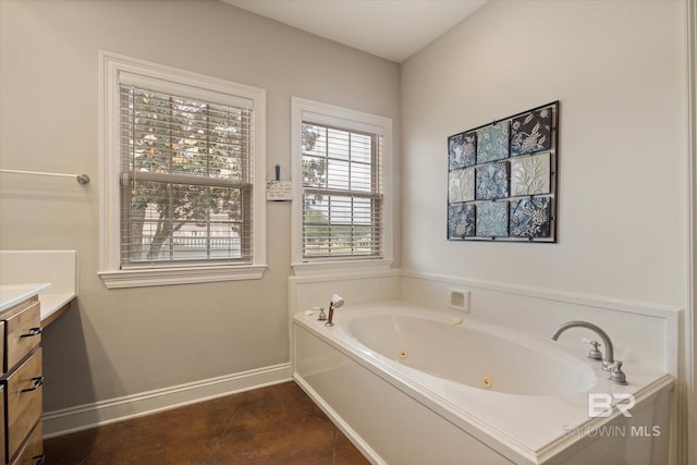 full bathroom with a tub with jets, tile patterned floors, vanity, and baseboards