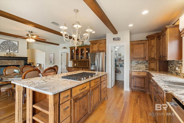 kitchen featuring beam ceiling, brown cabinetry, visible vents, appliances with stainless steel finishes, and ceiling fan with notable chandelier