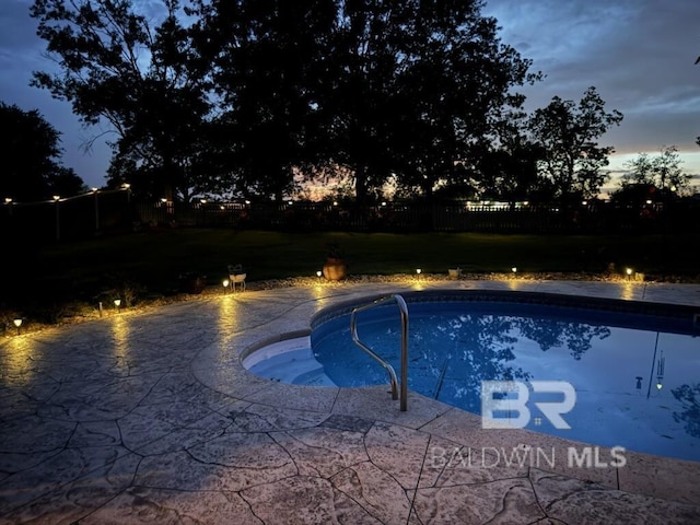 pool at dusk with an outdoor pool, a yard, a patio, and a fenced backyard