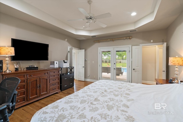 bedroom with visible vents, a raised ceiling, access to outside, and wood finished floors