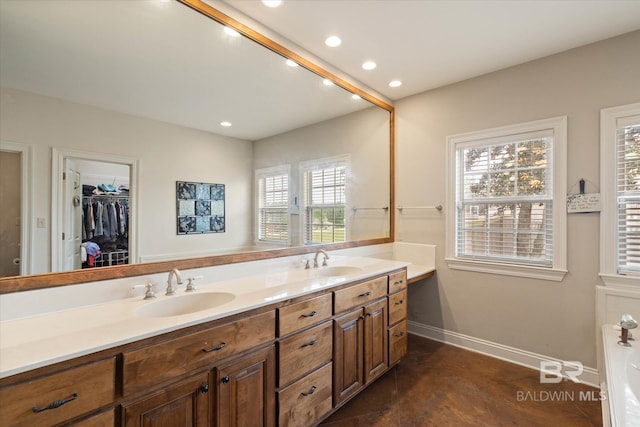 bathroom featuring double vanity, baseboards, recessed lighting, and a sink