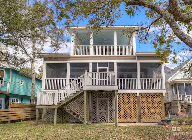 back of property featuring fence, stairway, a yard, a sunroom, and a balcony