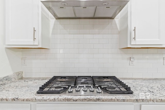 kitchen featuring extractor fan, stainless steel gas cooktop, white cabinetry, and light stone counters