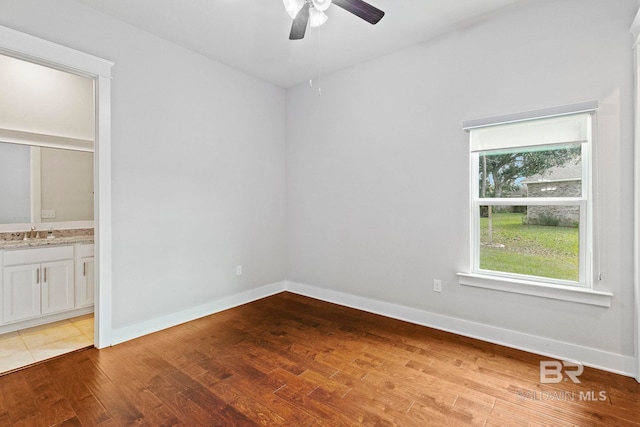 spare room with sink, wood-type flooring, and ceiling fan