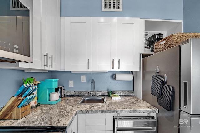 kitchen featuring white cabinetry, fridge, and sink