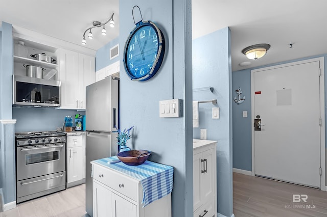 kitchen featuring visible vents, stainless steel appliances, light wood-style floors, white cabinetry, and open shelves