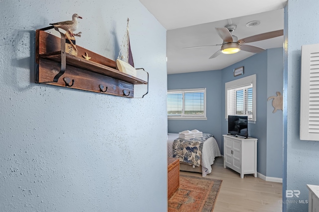 interior space featuring light wood-style floors, baseboards, and a ceiling fan