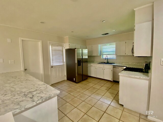 kitchen featuring white cabinetry, stainless steel appliances, light stone counters, sink, and light tile floors