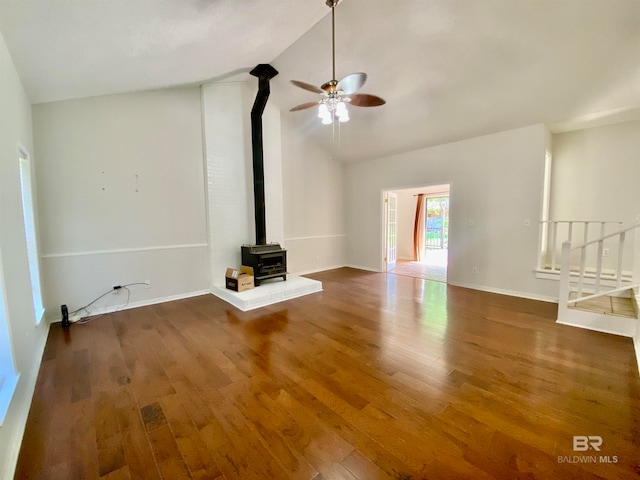 unfurnished living room with a wood stove, high vaulted ceiling, wood-type flooring, and ceiling fan