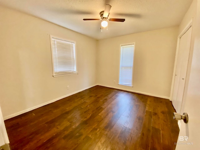 unfurnished room with a textured ceiling, ceiling fan, and dark wood-type flooring