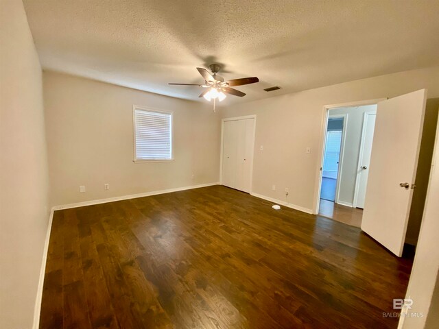 unfurnished room with ceiling fan, dark hardwood / wood-style floors, and a textured ceiling