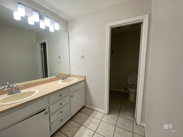 bathroom featuring tile flooring, double vanity, toilet, and a textured ceiling