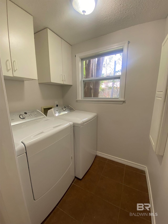 washroom featuring washing machine and dryer, washer hookup, dark tile flooring, cabinets, and a textured ceiling