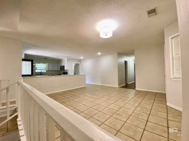 empty room featuring a textured ceiling, sink, and light tile flooring