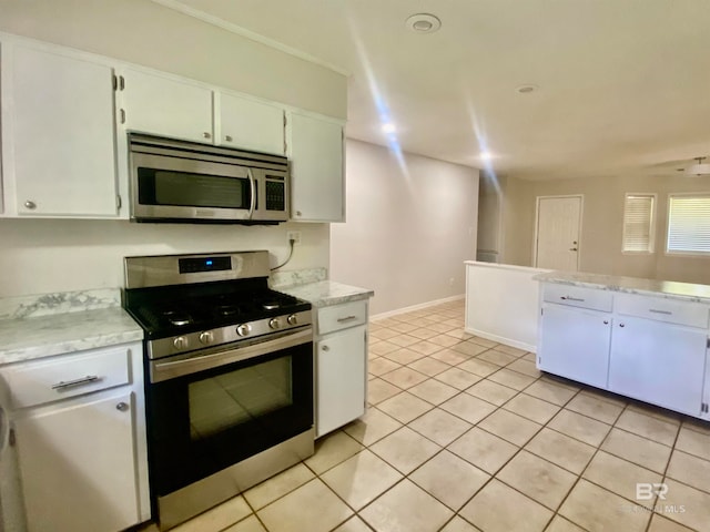 kitchen featuring stainless steel appliances, white cabinets, light tile floors, and light stone countertops