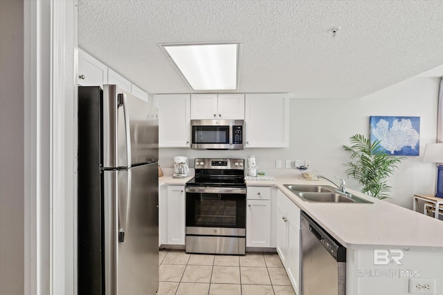 kitchen with stainless steel appliances, light countertops, white cabinetry, a sink, and a peninsula