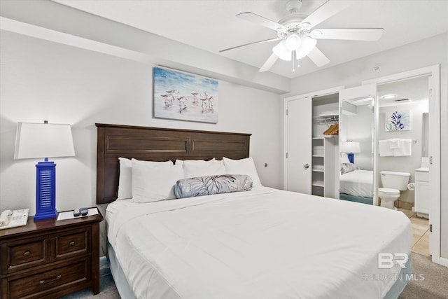 carpeted bedroom with ensuite bathroom, a closet, and a ceiling fan