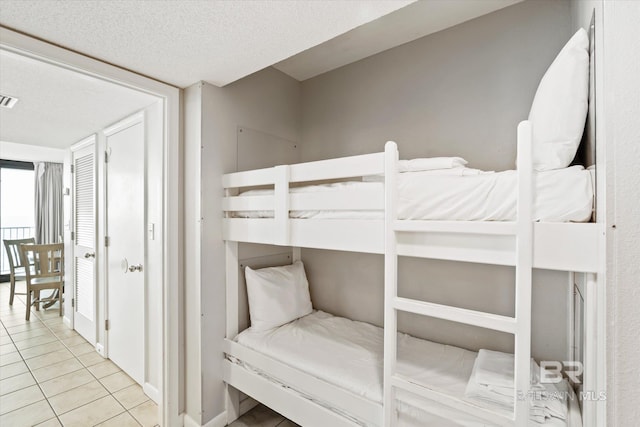 tiled bedroom with visible vents and a textured ceiling