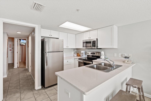 kitchen with stainless steel appliances, a peninsula, a sink, visible vents, and light countertops