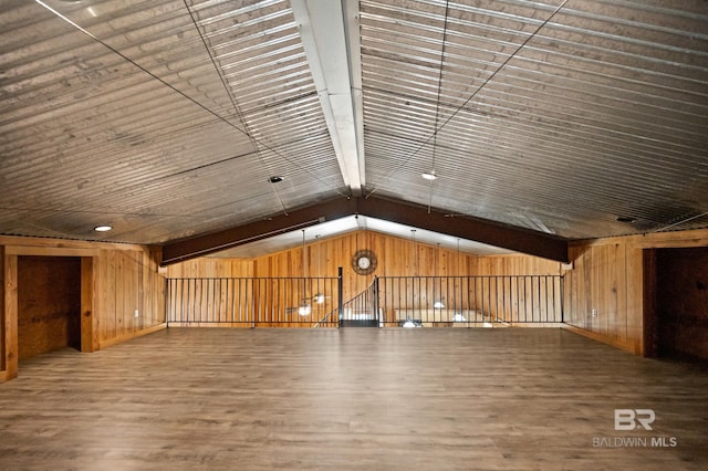 bonus room featuring dark wood-type flooring, vaulted ceiling, and wood walls